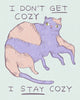 Illustration of a cat with text 'I don't get cozy, I stay cozy' on a light blue background, drawing by artist Heather Buchanan